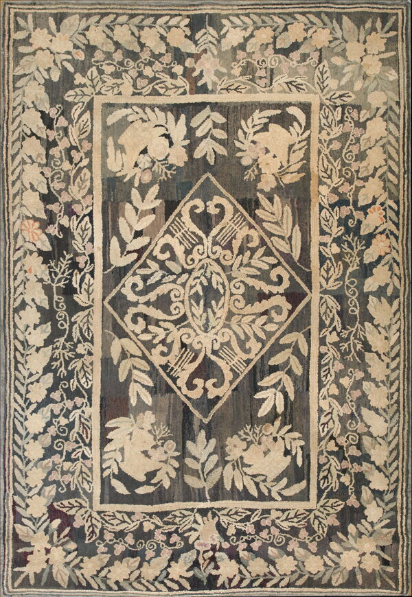 Textured hooked rug displaying dense beige and pink floral patterns and a central diamond on a dark, variegated field.