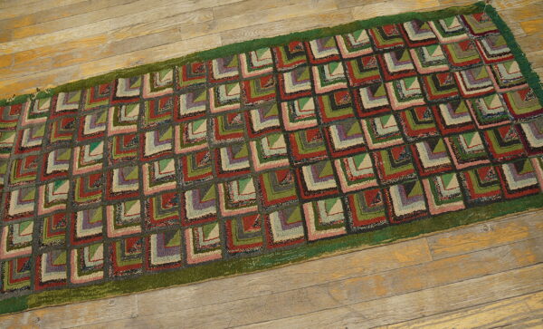 Textured runner with red, green, gray, and beige geometric patchwork squares on rustic wood flooring.