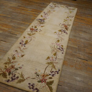 Textured cream runner rug featuring colored floral vine borders on distressed wide plank wood flooring.