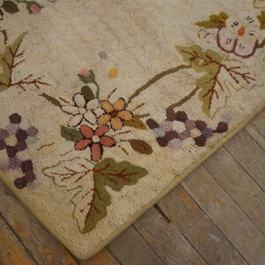 Beige textured rug with pink, purple, and green floral clusters on distressed, wide plank wood flooring.
