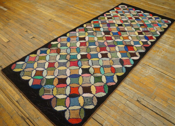 Multicolored hooked runner rug featuring a circular quilt-like pattern on rustic wood floorboards.