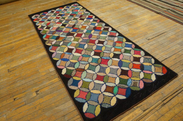 A multicolored, high-pile rug runner with an interlocking geometric pattern rests on distressed yellow-toned wood flooring.