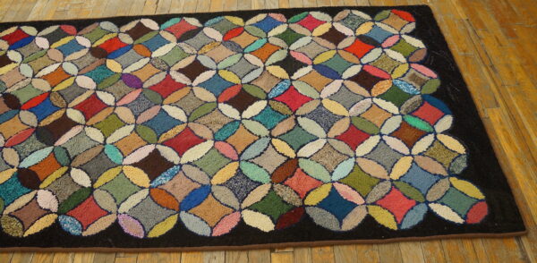 Multicolored hooked rug featuring a highly textured quatrefoil quilt pattern on natural wood flooring.