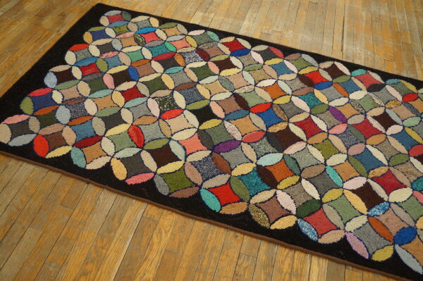 Multicolored runner rug featuring a textured patchwork circle design and a dark border on aged hardwood floors.