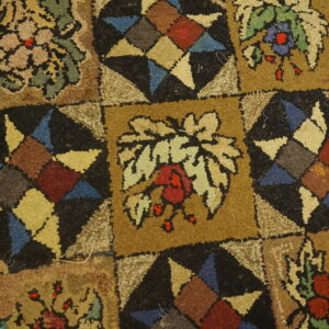 Multicolored looped pile rug featuring a block pattern with tan florals and black geometric starbursts.