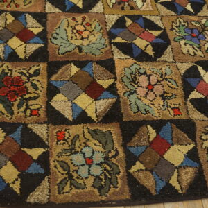 Textured, multicolored rug featuring a checkerboard pattern of floral and star motifs on light wood floors.