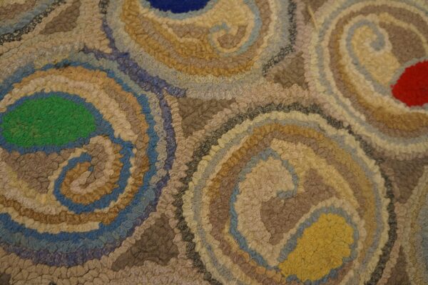 Textured rug close-up featuring large swirls of blue, green, red, yellow, and various neutral tones.