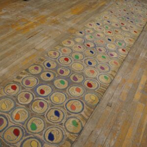 Tan runner rug featuring repeating circles with colorful centers on a distressed wood floor.