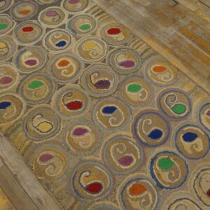 Muted rug runner with colorful red, blue, and green paisley motifs set within circular tan patterns on wood floors.