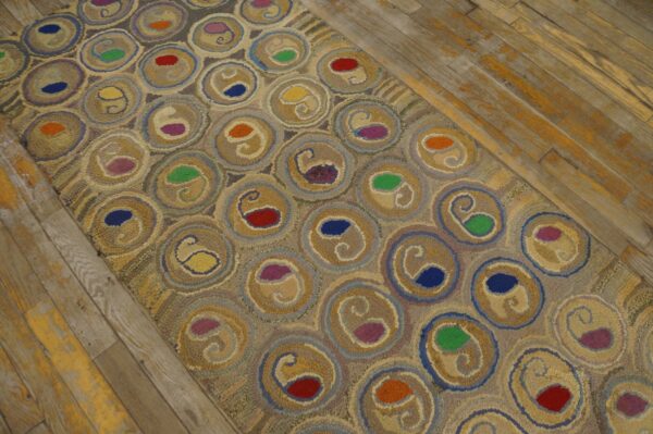 Muted rug runner with colorful red, blue, and green paisley motifs set within circular tan patterns on wood floors.