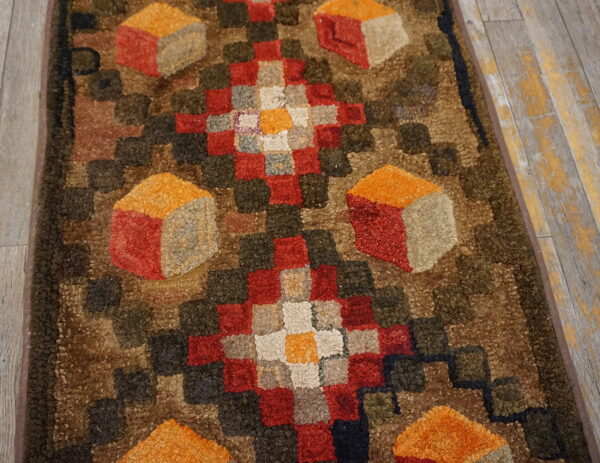 Chunky hooked runner featuring geometric diamonds and cube patterns in red, orange, brown, and green on wood flooring.