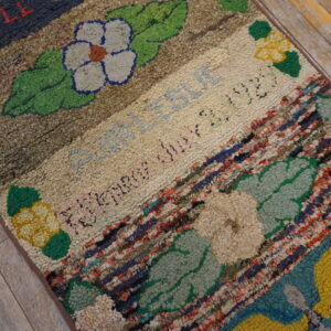 High-pile rug with bands of flowers, text, and braided multicolor stripes rests on rustic wood floors.