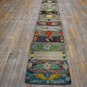 Highly textured, multicolored runner rug featuring pictorial scenes and visible text lays on a distressed wood floor.