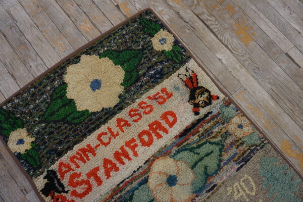 Coarse texture rug with multicolored floral and text patterns lying on weathered gray wood flooring.