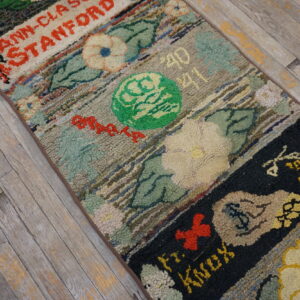 Multicolored hooked runner rug with segmented floral, text, and geometric patterns lies on distressed light wood planks.