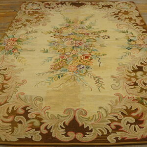 Cream and brown rug with an elaborate multicolored floral and scroll design on wood planks.