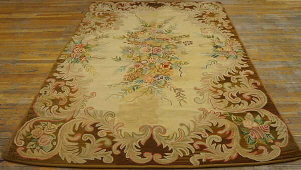 Cream and brown rug with an elaborate multicolored floral and scroll design on wood planks.