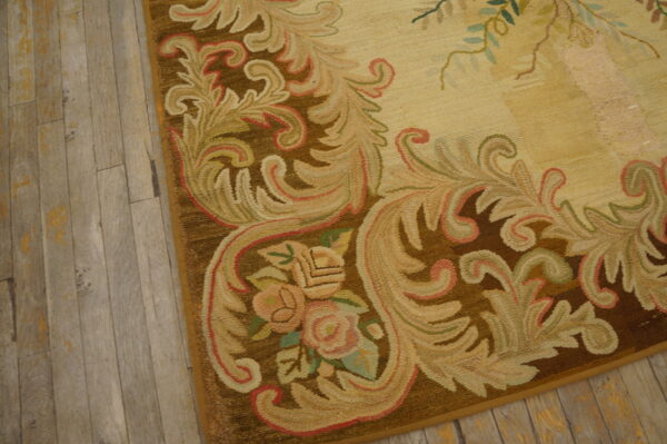Close-up of a low-pile rug featuring a brown, beige, and pink floral border on rustic wood flooring.