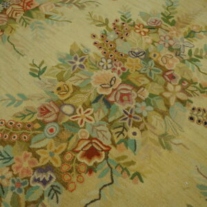 Hooked rug texture in pale yellow showing a detailed cluster of multicolored pink, purple, and green florals.