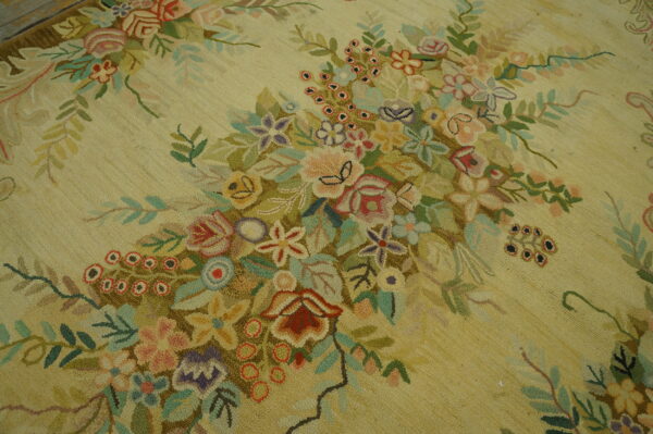 Hooked rug texture in pale yellow showing a detailed cluster of multicolored pink, purple, and green florals.