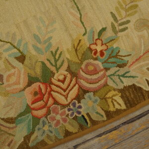 Textured, high-pile beige rug with ornate pink and green floral motif borders rustic wood flooring.