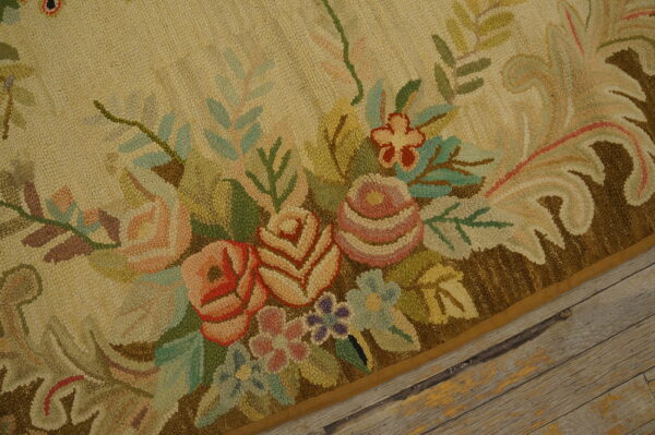 Textured, high-pile beige rug with ornate pink and green floral motif borders rustic wood flooring.