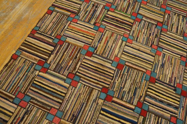 Textured rug with multicolored horizontal and vertical striped blocks linked by red and teal squares on wood flooring.