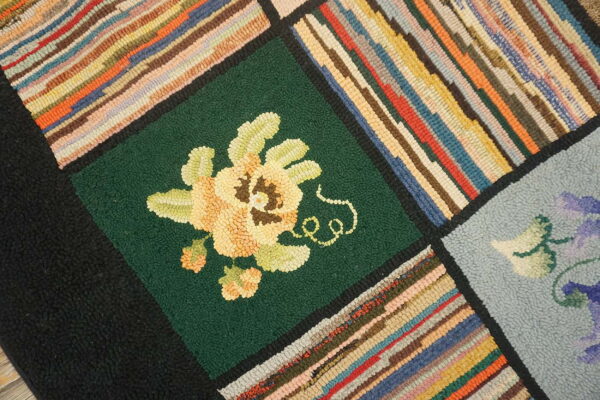 Textured patchwork rug with bold multicolored stripes and a yellow flower motif on a deep green square.