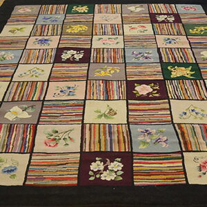 Multi-colored patchwork rug with alternating floral motifs and variegated striped squares on a wooden floor.
