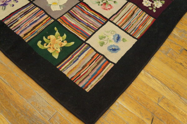 Detail of a hooked rug showing floral and multicolored striped squares bordered in black on a light wood floor.