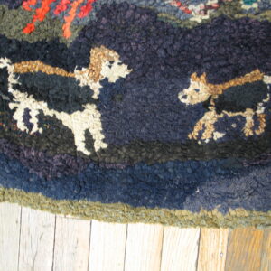 Dark blue, green, and red textured rug featuring two tan and white stylized dogs on wood flooring.