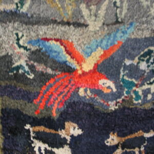 Chunky pile rug with a vibrant parrot design in red, blue, gray, and navy on wood flooring.
