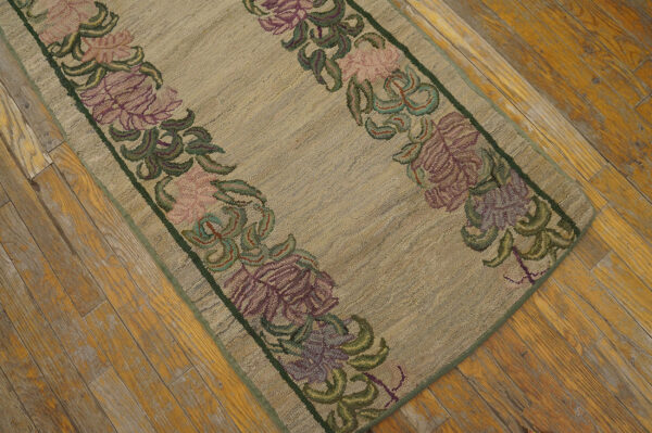 Low-pile beige runner rug with purple and pink floral borders on distressed wooden flooring.