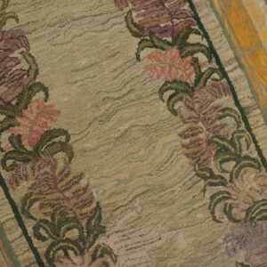 Against a distressed wood floor, this beige low-pile runner rug is highlighted by soft purple and pink floral borders.