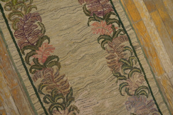Against a distressed wood floor, this beige low-pile runner rug is highlighted by soft purple and pink floral borders.