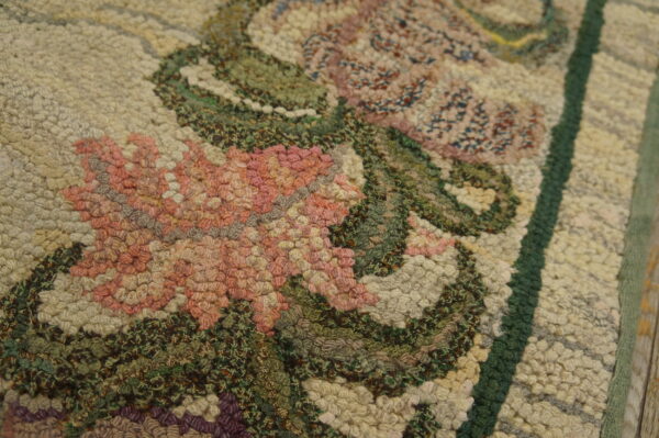 Set on a distressed wooden floor, a low-pile beige runner rug showcases gentle purple and pink floral borders.