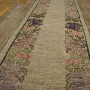 A high-pile beige runner with pink and green floral patterns lies on distressed wood flooring.