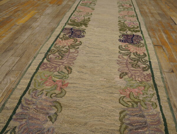 A high-pile beige runner with pink and green floral patterns lies on distressed wood flooring.