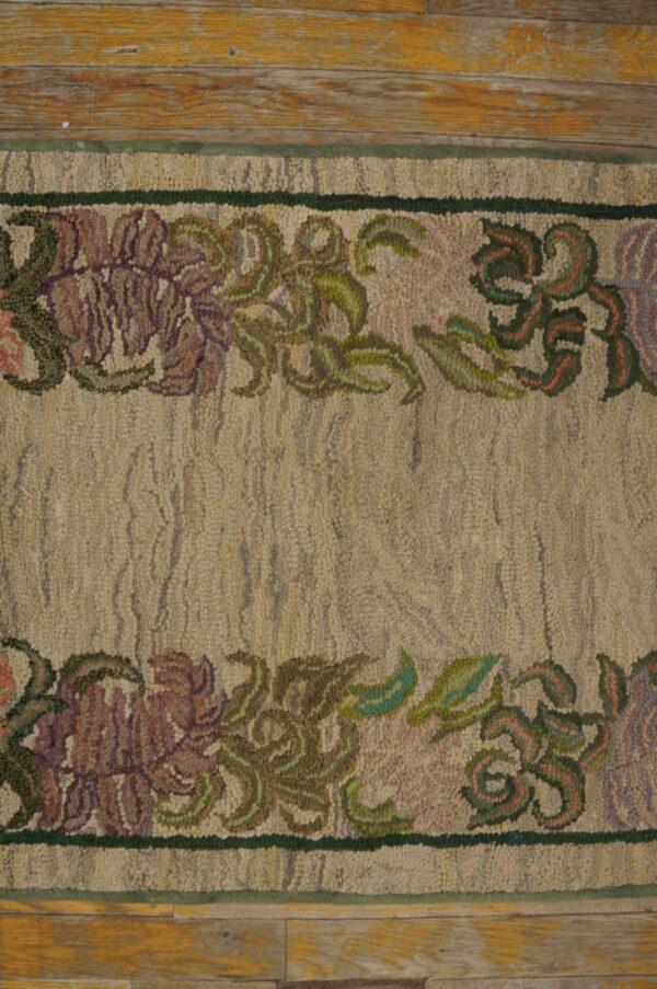 Photographed on a distressed wooden floor, this low-pile beige runner rug is framed by delicate purple and pink floral borders.