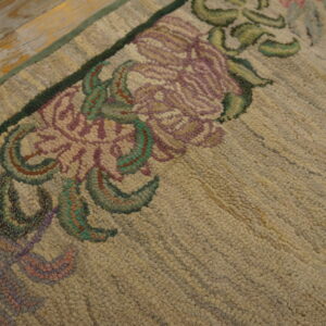 Low-pile beige runner rug with delicate purple and pink floral borders, photographed on a distressed wooden floor.