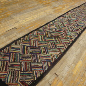 Textured, high-pile runner with a multicolored patchwork pattern lies on worn wooden floorboards.