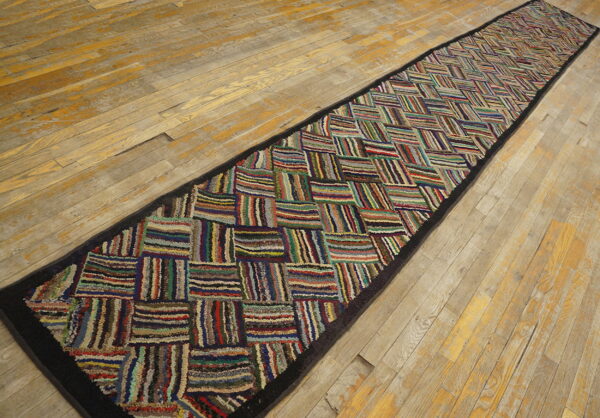 Textured, high-pile runner with a multicolored patchwork pattern lies on worn wooden floorboards.