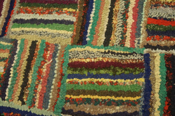 Macro view of a chunky, multicolored textured rug featuring striped sections and geometric block patterning.