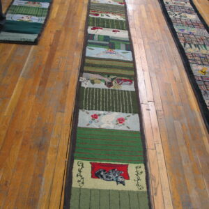 Long textured runner rug with colorful pictorial segments rests on rustic wood flooring.
