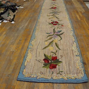 Beige looped floral runner with red and blue accents rests on a yellow-toned wood floor.