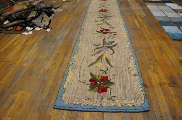 Beige looped floral runner with red and blue accents rests on a yellow-toned wood floor.