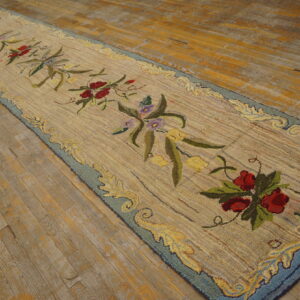 Textured beige runner rug with colorful floral motifs and a blue border rests on rustic wood floors.