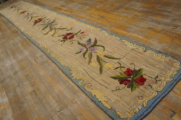 Textured beige runner rug with colorful floral motifs and a blue border rests on rustic wood floors.
