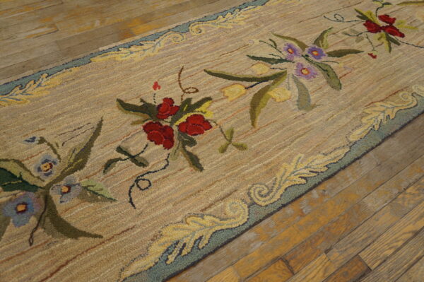 Textured beige runner with a floral pattern of red, purple, and yellow on old hardwood flooring.