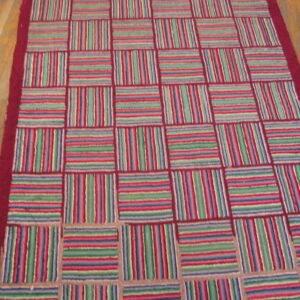 Multi-colored striped blocks in red, green, and blue form a checkerboard pattern on light wood flooring.